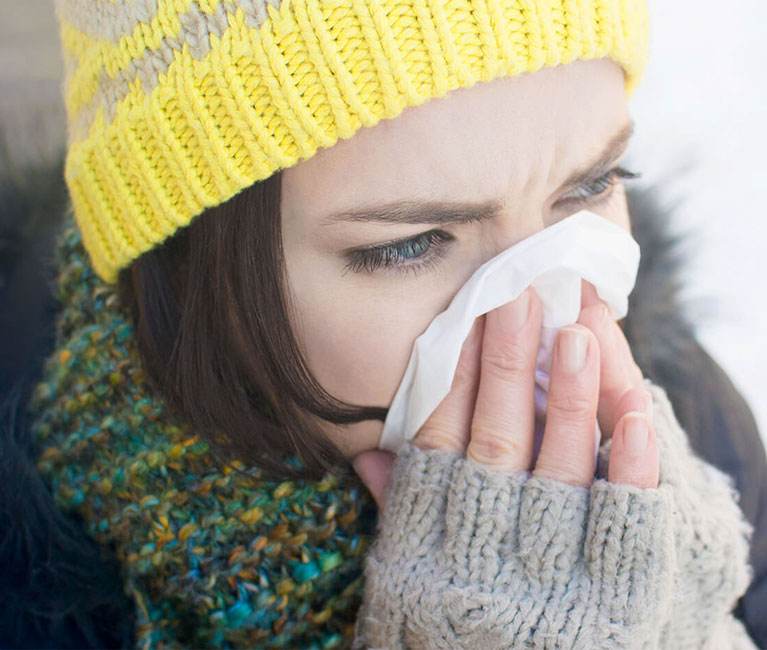 Femme habillée de vêtements d'hiver en train de se moucher